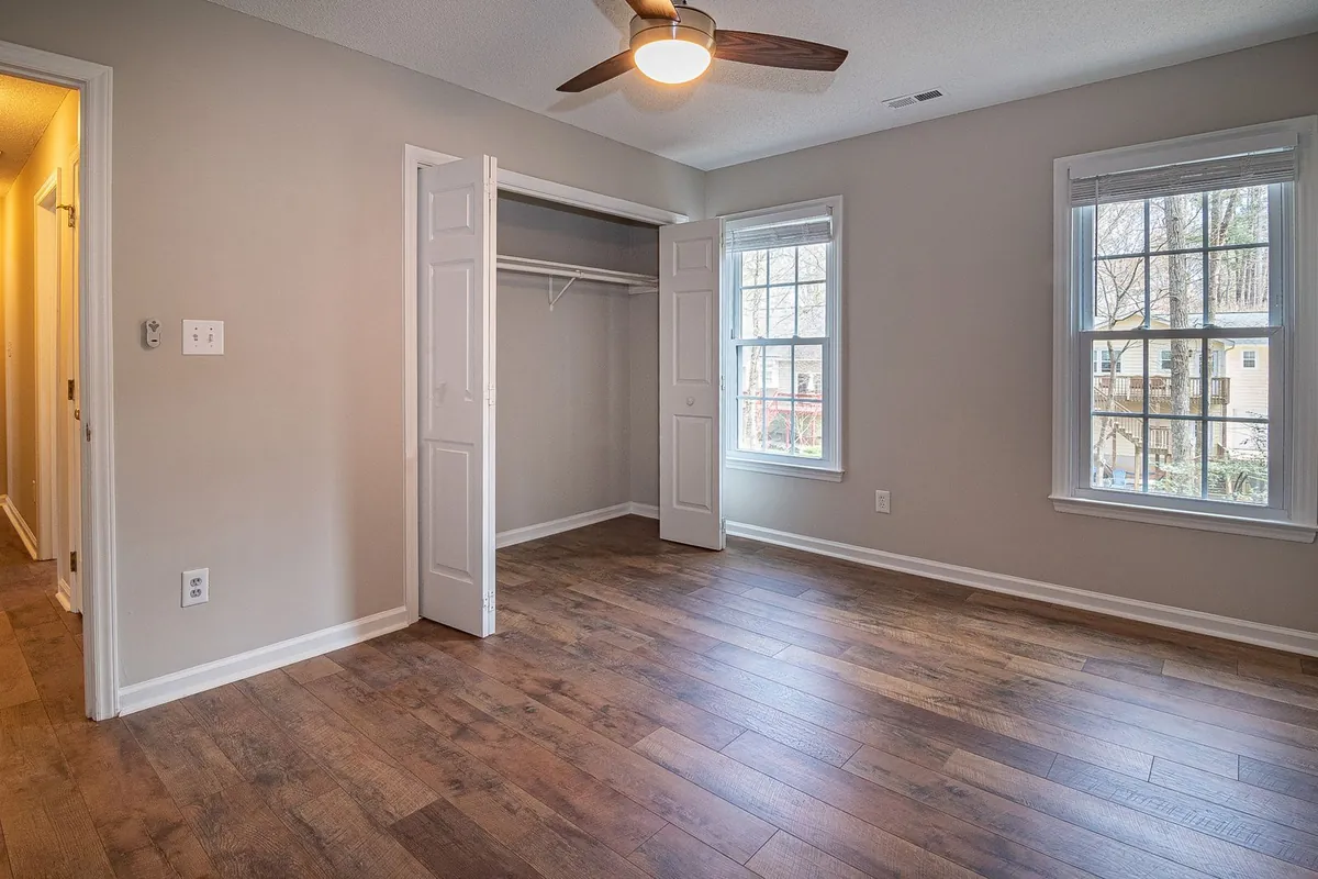 Empty bedroom with wood floor, ceiling fan and open closet