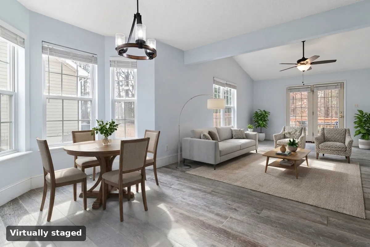 The same room virtually staged with a sofa, chairs, rug and a dining table under the chandelier