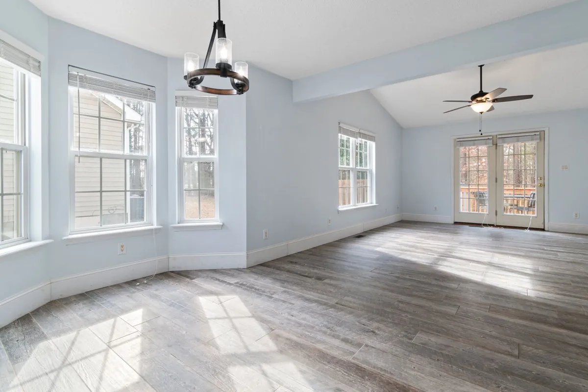 Empty living and dining room with grey wood floor and bay windows